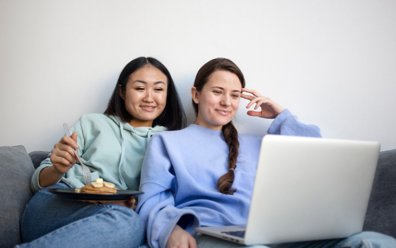 friends watching a video on laptop, group travels, January 2025, UK